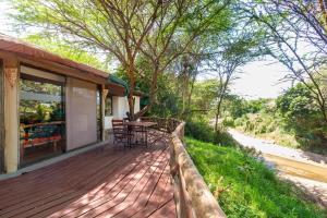 a wooden deck with a table and chairs on a house at PrideInn Mara Camp & Cottages in Talek
