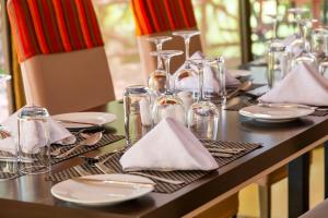 a table with plates and glasses and napkins on it at PrideInn Mara Camp & Cottages in Talek