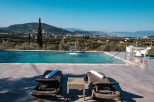 a swimming pool with two chairs and a table at VILLA KONSTANTINA in Nafplio