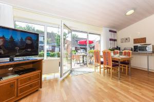 a living room with a television and a table with chairs at Ferienhaus Weiße Robbe in Bensersiel