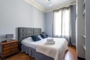 una camera da letto con un letto con cuscini blu e una finestra di Londres a Nizza
