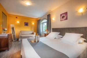 - une chambre avec un grand lit blanc et une chaise dans l'établissement Le Coq Hardi, à Pouilly-sur-Loire