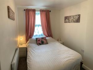 a small bedroom with a white bed with a window at Lovely 2-Bed Apartment Central Skegness Beach in Skegness