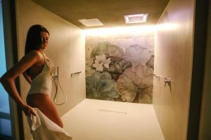 ネイヴェにあるLanghe Country Houseの女性が絵画を持つ浴室に立っている