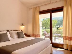 a bedroom with a bed and a sliding glass door at Punta D'Acu Country Resort in Arzachena