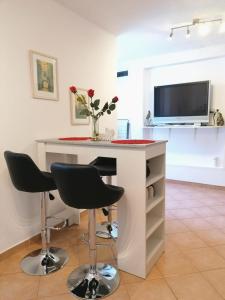 a kitchen with a white island with chairs and a tv at Matic Apartments in Split