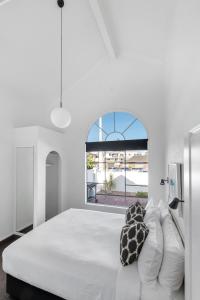 a white bedroom with a large white bed with pillows at The Mission Belle Motel in Mount Maunganui