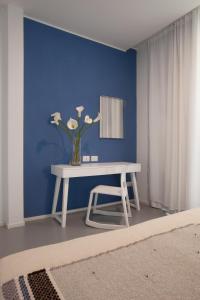 a table with a vase of flowers on a blue wall at Residenza Dante in Nuoro