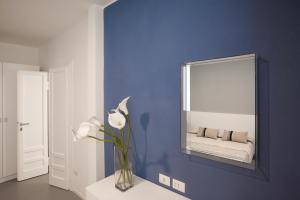 niebieski pokój z lustrem i wazą z białymi kwiatami w obiekcie Residenza Dante w mieście Nuoro