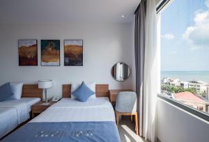a hotel room with two beds and a large window at Delight Hotel in Quy Nhon