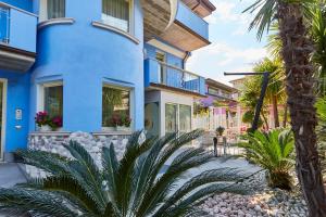 una casa azul con palmeras delante en Villa Azzurra Depandance con piscina, en Desenzano del Garda