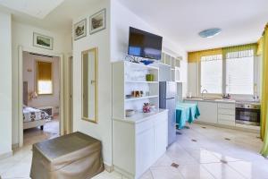 a kitchen with white cabinets and a tv on a wall at Villa Azzurra Depandance con piscina in Desenzano del Garda