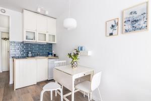 a kitchen with white cabinets and a white table and chairs at Nice Sopot in Sopot