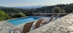 a swimming pool with chairs sitting around it at Villa Rokanes Glass Stone with Pool in Kouvéllai