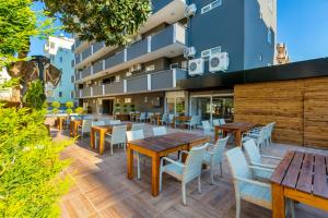 an outdoor patio with wooden tables and chairs at Royalisa City Apart Hotel in Alanya