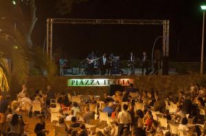 a crowd of people sitting in chairs in front of a stage at Le Residenze di Piazza Italia in Costa Rei