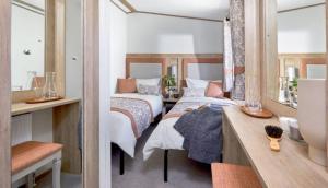 a bedroom with two beds and a vanity with a mirror at Bluebell Lodge in South Cerney