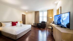 um quarto de hotel com uma cama e uma televisão de ecrã plano em Rocana Hotel em Kuantan