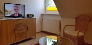 a living room with a tv on a wooden dresser at Ferienwohnung-Floppy-Hansi-OG-3 in Sankt Peter-Ording