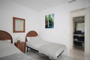 een witte slaapkamer met 2 bedden en een spiegel bij Bear Holiday - Apartment Beau with Sea View in Moraira near the Beach in Moraira