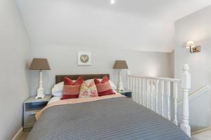 a bedroom with a white bed with red pillows at Acorn Cottage in Loughborough