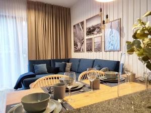 ein Wohnzimmer mit einem Tisch und einem blauen Sofa in der Unterkunft Apartamenty Baltic Park - visitopl in Świnoujście