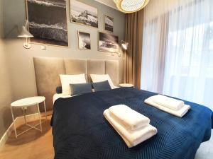 ein Schlafzimmer mit einem blauen Bett und Handtüchern darauf in der Unterkunft Apartamenty Baltic Park - visitopl in Świnoujście