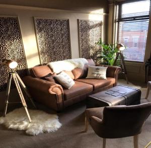 a living room with a brown couch and a table at Kingsmere Guest House in South Shields