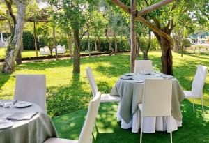 two tables and white chairs in a garden at Hotel Alpha in Sant'Agnello