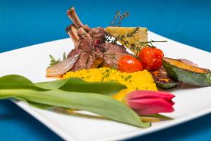 a white plate of food with meat and vegetables at Hotel Alpenhof in Unterbäch