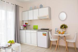a small kitchen with white cabinets and a small table at Windmill Beach Apts II by Estia in Malia
