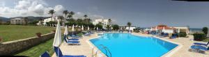 a large swimming pool with blue lounge chairs and the ocean at Windmill Beach Apts II by Estia in Malia