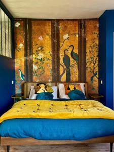 - une chambre avec un grand lit orné d'une peinture murale dans l'établissement Aux Jolies Sources, à Saint-Aubin-sur-Scie