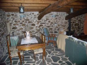 a room with a table and chairs and a stone wall at Casa Rural A Pasada in Cedeira
