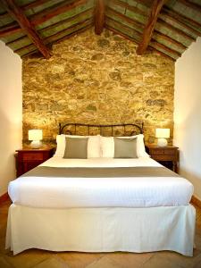 a bedroom with a large white bed with a stone wall at Punta D'Acu Country Resort in Arzachena