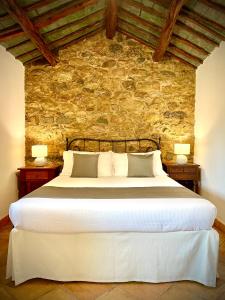 1 dormitorio con 1 cama blanca grande y pared de piedra en Punta D'Acu Country Resort, en Arzachena