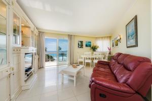 a living room with a red leather couch and a table at Frente al mar in Cala Millor