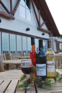 tres botellas de vino y una copa sobre una mesa de madera en Lied Lodge at Arbor Day Farm, en Nebraska City