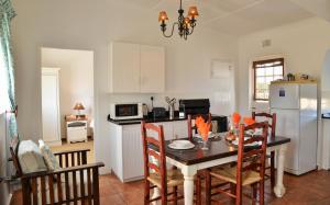 a kitchen with a table with chairs and a refrigerator at De Hoop Collection - Equipped Cottages in De Hoop Nature Reserve