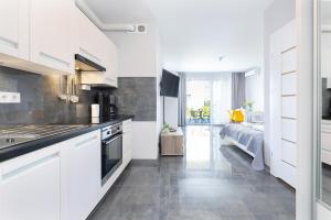 a kitchen with white cabinets and a bed in the background at Apartament Paraiso by Renters in Łukęcin