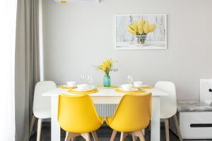 a dining room with a white table and yellow chairs at Apartament Paraiso by Renters in Łukęcin