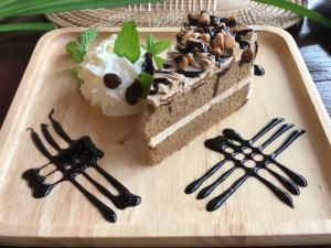 um pedaço de bolo numa bandeja de madeira com pinças em Papai Country Lodge SHA em Ban Mae Pong