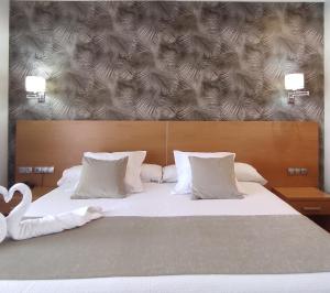 una cama grande con almohadas blancas y un cisne en ella en Peregrina Hotel, en Sanxenxo