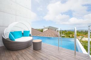 a wicker chair sitting on a deck next to a swimming pool at E-horizon Resort Premium 瀬底E in Sesoko