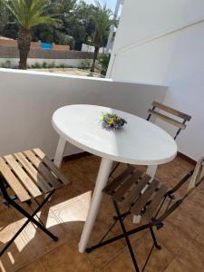 a white table with two chairs and a flower on it at Appartamento Costamar 14, Es Pujols, ALTA TURISTICA in Es Pujols