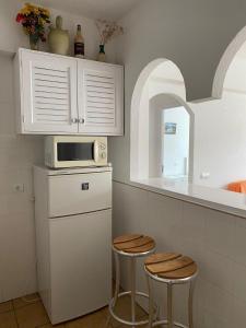 a kitchen with a microwave and two stools at Appartamento Costamar 14, Es Pujols, ALTA TURISTICA in Es Pujols