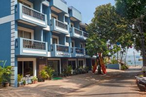 a blue building with a tree in front of it at The Hawaii Comforts Panjim in Panaji