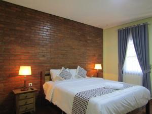 um quarto com uma cama e uma parede de tijolos em Nia Maretta House Syariah em Magelang