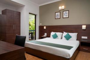 a bedroom with a bed and a desk and a table at The Hawaii Comforts Panjim in Panaji