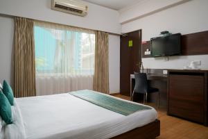a bedroom with a bed and a desk and a television at The Hawaii Comforts Panjim in Panaji